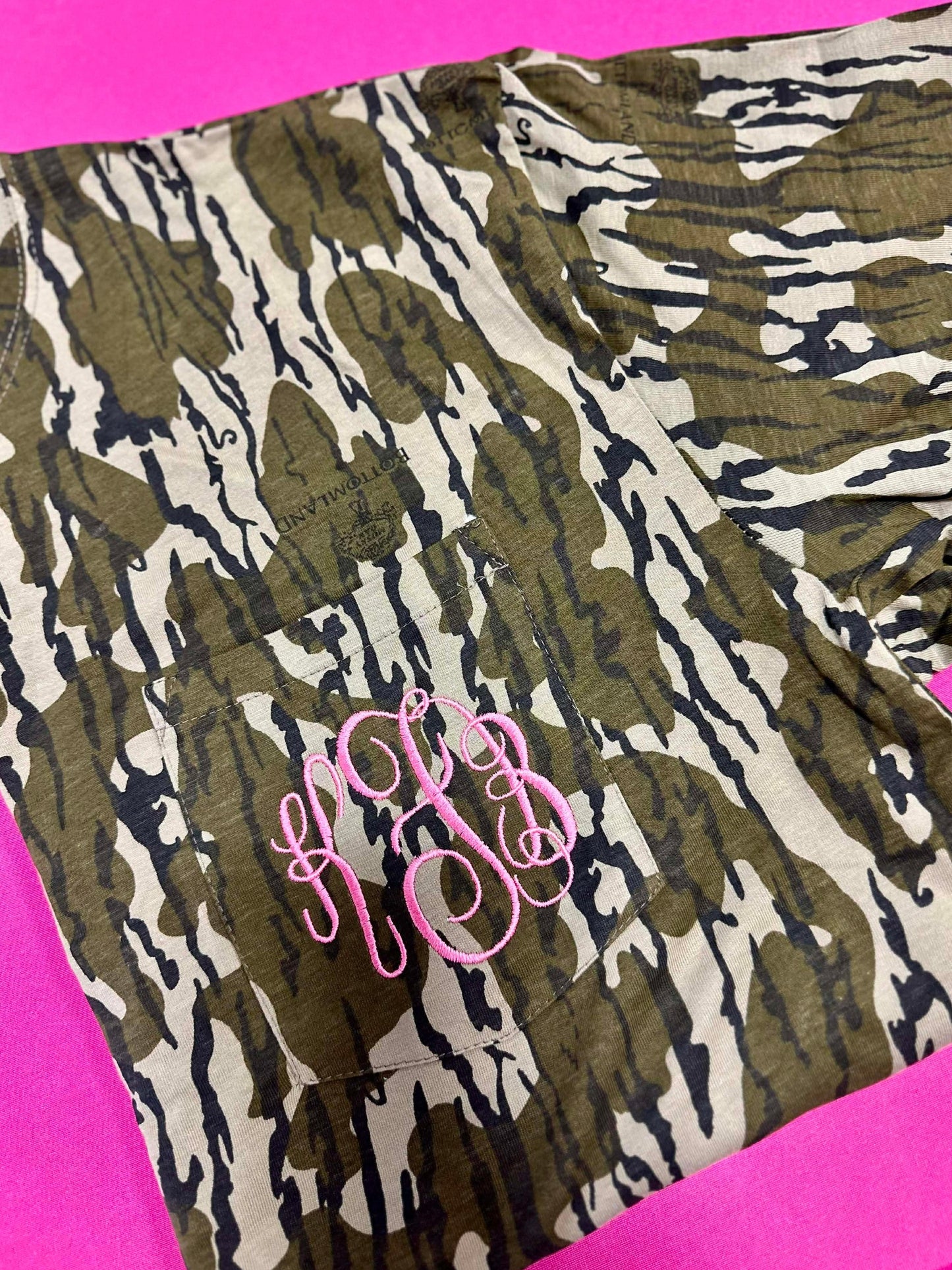 Camouflage patterned fabric with pink monogram on a pink background
