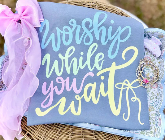 Decorative sign with 'Worship while you wait' text on a blue background, surrounded by decorative elements.
