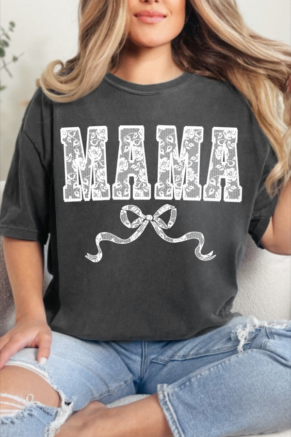 A person wearing a black t-shirt with the text 'MAMA' printed in white, decorated with a white lace-style pattern and a bow at the bottom.