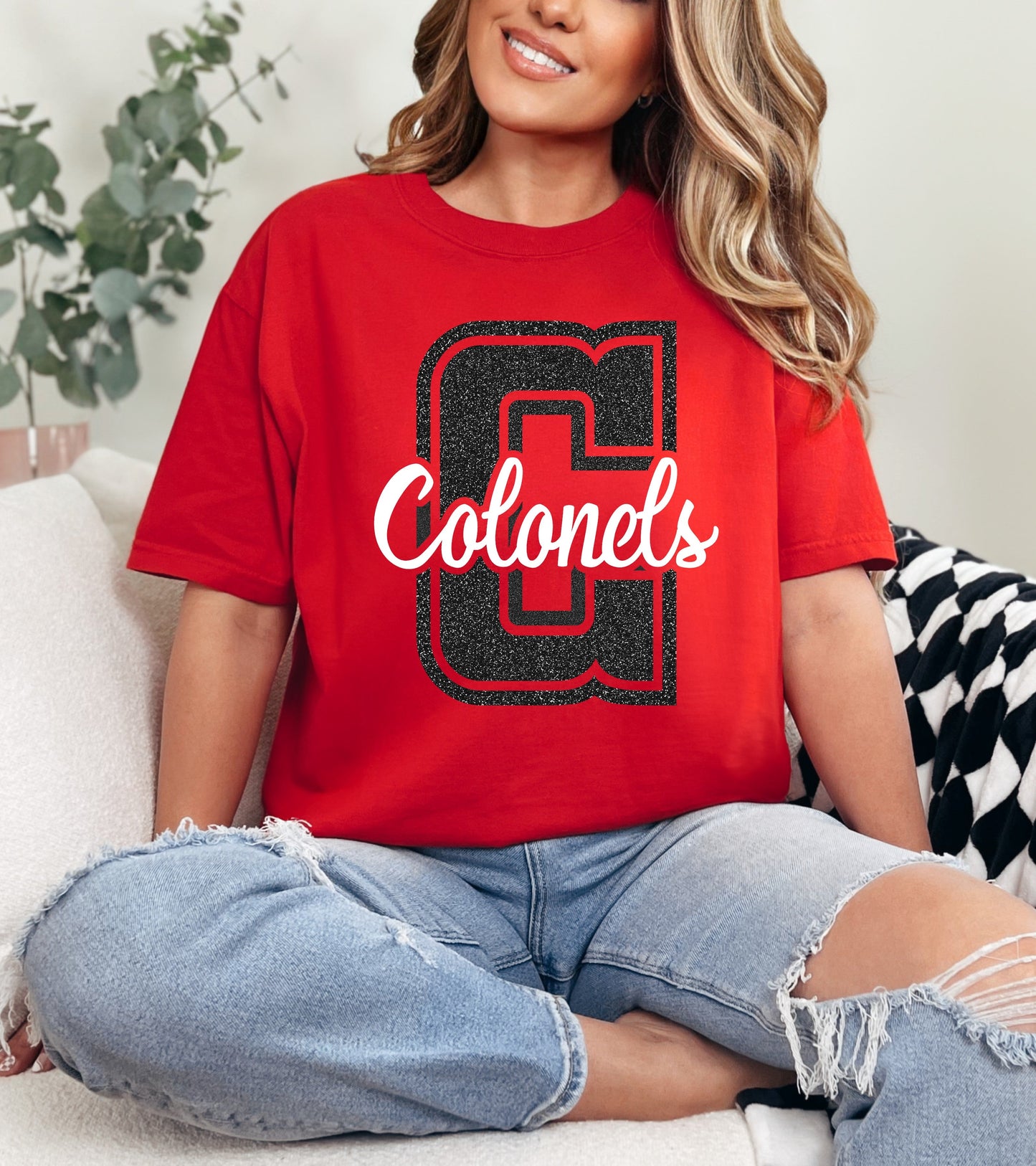 Person wearing a red 'Colonels' t-shirt sitting on a couch.