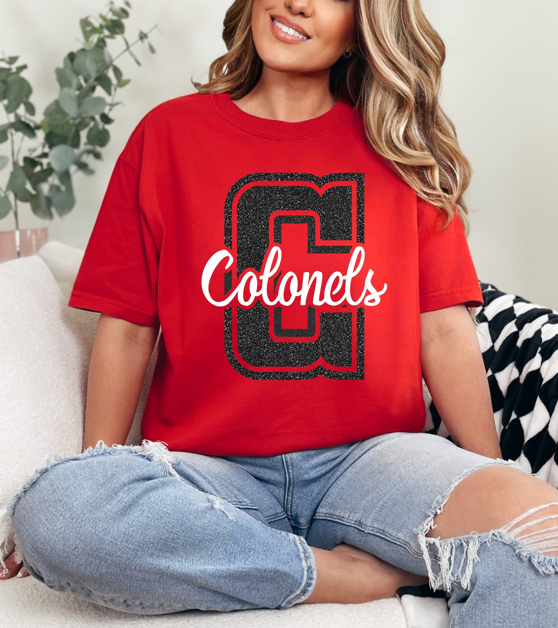 Person wearing a red 'Colonels' t-shirt sitting on a couch.