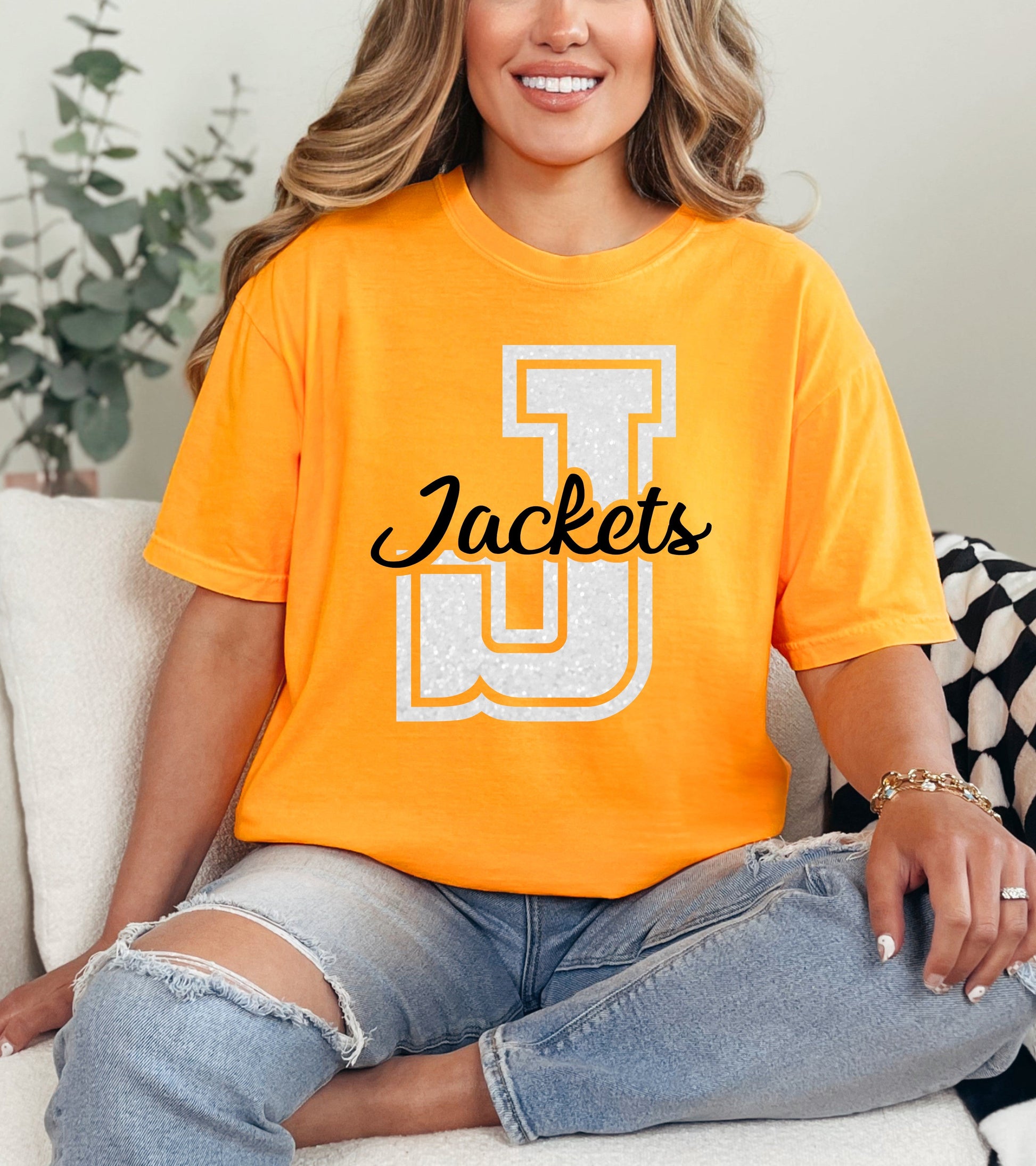 Person wearing an orange 'Jackets' t-shirt sitting on a couch.